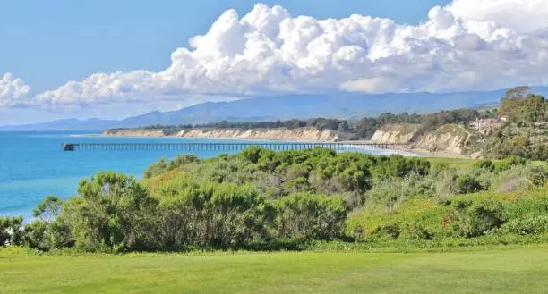 Golf Course Overlooking Ocean and Pier in Santa Barbra California. Perfect balance of white clouds, grass, and ocean pier that are laid out in a parallel pattern.