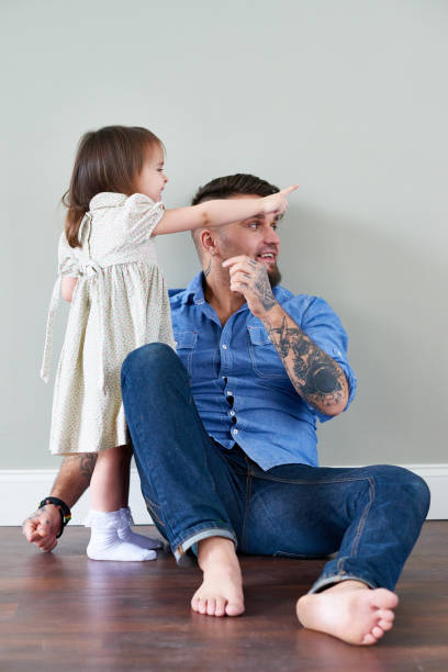 istock Playful girl with father sitting on floor 1162196340