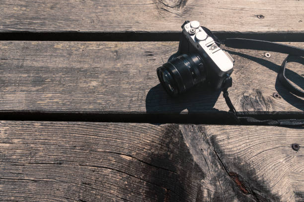 Vintage style grey and black photo camera on wooden table outdoors in the sun view from above
