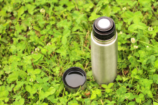 istock metal thermos with a lid on the green grass 1162198429