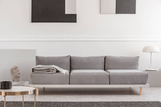 istock Grey sofa in white interior with abstract paintings on the wall 1162200247