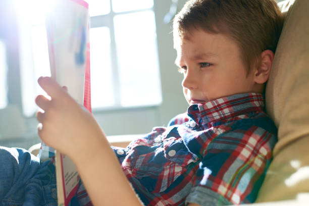 Kid reading magazine on couch at home