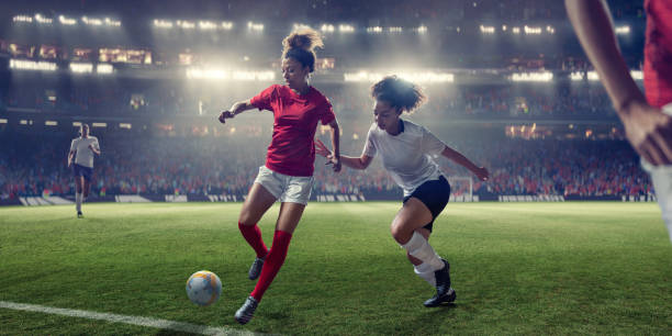 jogadores de futebol das mulheres no mid-action durante o jogo no estádio do projector - futebol feminino - fotografias e filmes do acervo