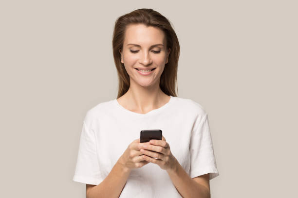 istock Smiling young woman using cellphone, looking at screen, chatting online 1162203174