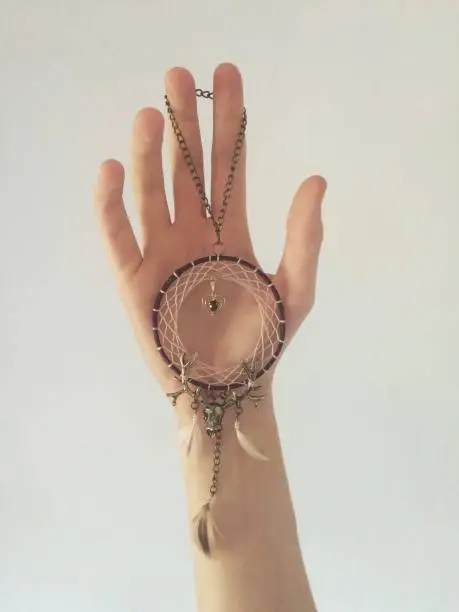 human hand delicately holding a hand made crafted dream catcher