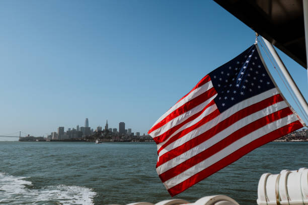 SAN FRANCISCO, USA - JULY 2019: American flag waving on a boat, with San Francisco skyline in the background