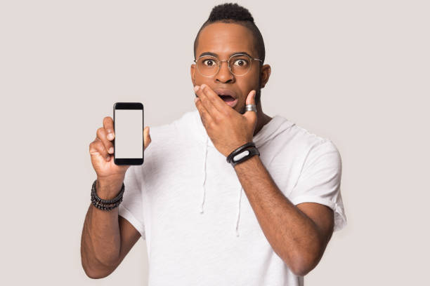 istock African astonished man showing phone screen feels shocked studio shot 1162206914