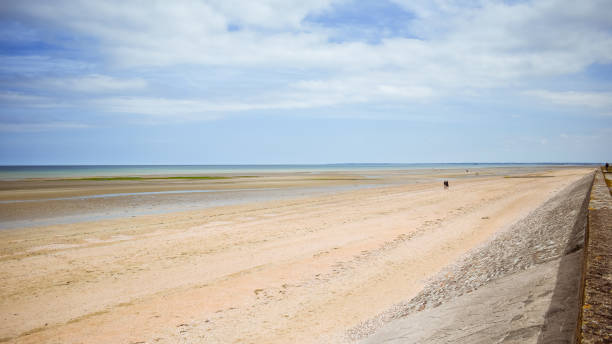 Long calm beach with blue cloudy sky. Normandy, France.