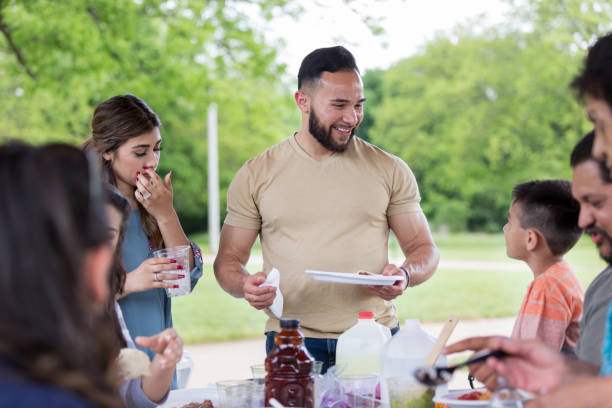 istock Uncle and nephew talk while eating lunch at family picnic 1162213538