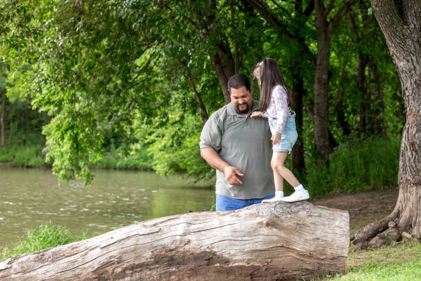 istock Dad helps daughter balance on log 1162215307