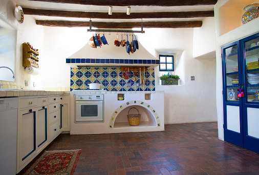 Rustic Southwest USA Kitchen: Old-fashioned brick floor, ceiling beams, counters, drawers, oven. Wide angle. Shot in Santa Fe, NM.