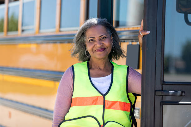 Confident African American school bus driver Portrait of beautiful mature African American female school bus driver standing in front of a school bus. school buses stock pictures, royalty-free photos & images