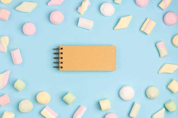 istock Blue paper background with marshmallow and notepad. Place for your text. Cozy sweet background 1162226011