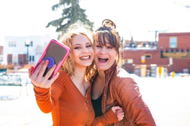 istock Mother and Daughter Having Fun Taking Selfies Outdoors in Winter 1162229899