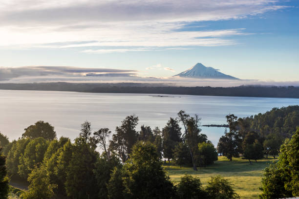The Lakes Region is located on South of Chile and formed because of tectonic plates and land collapse on the lake location. It is an amazing place for landscape photographers like me, water surrounded by deep forests with huge trees and volcanoes like the Osorno and Puntiagudo. el increíble volcán osorno sobre las nubes en una vista desde el lago rupanco, el tress dentro del bosque y las nubes lo que lo convierte en un impresionante paisaje volcánico. una cumbre perfecta cubierta de nieve cono. al sur de chile.