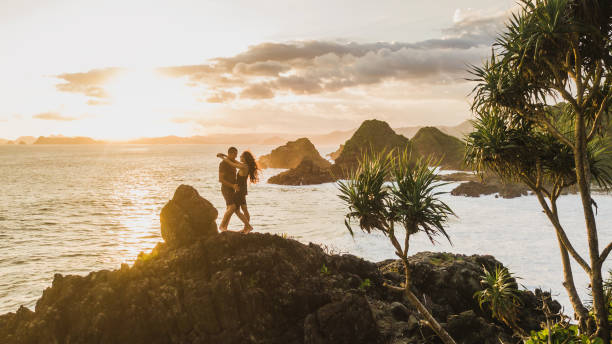 Couple enjoying sunset with amazing ocean and mountain view. Travel concept, panoramic shot, wanderlust. stock photo