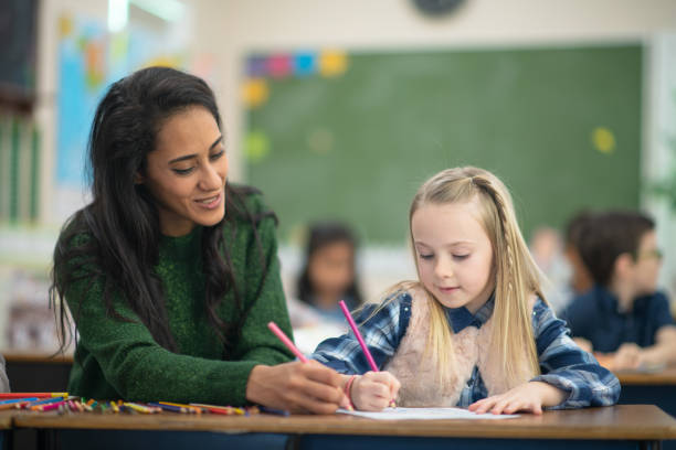 istock Teacher helps her female blonde student with her assignment in class 1162241506