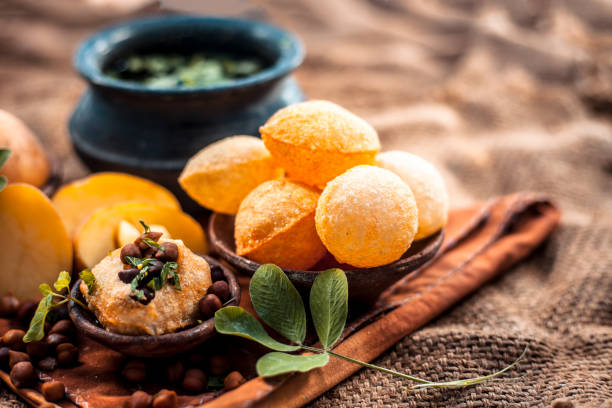 Famous Indian & Asian street food dish i.e. Panipuri snack in a clay bowl along with its flavored spicy water in another clay vessel. Entire consisting raw ingredients present on the surface. Famous Indian & Asian street food dish i.e. Panipuri snack in a clay bowl along with its flavored spicy water in another clay vessel. Entire consisting raw ingredients present on the surface. panipuri stock pictures, royalty-free photos & images