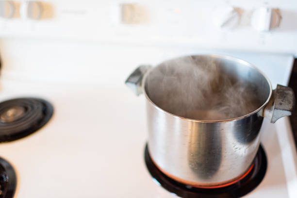빈티지 스토브 상단의 클로즈업 흰색 조리대와 스테인리스 냄비와 복고풍 부엌에서 증기 요리 - steam saucepan fire cooking 뉴스 사진 이미지