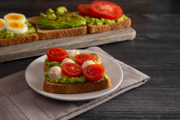istock Tomato and Mozzarella Avocado Toast on a Dark Wood Table 1162244757