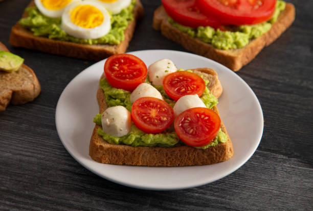 istock Tomato and Mozzarella Avocado Toast on a Dark Wood Table 1162244761