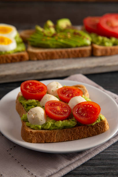 istock Tomato and Mozzarella Avocado Toast on a Dark Wood Table 1162244830