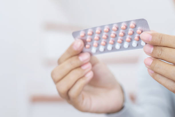 woman hands opening birth control pills in hand. eating contraceptive pill. - contraceção imagens e fotografias de stock