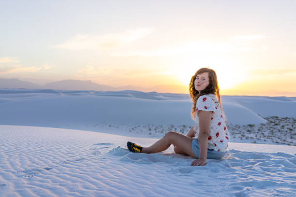 девушка, сидящая в белых песках дюн национального памятника в нью-мексико вид заката на горизонте - side view southwest usa horizontal sun стоковые фото и изображения