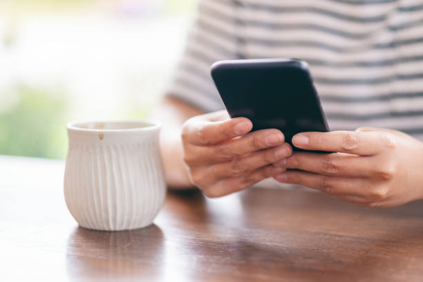 istock a woman holding  and using mobile phone with coffee cup on wooden table 1162251644