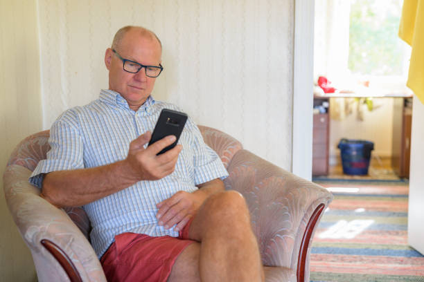 istock Senior Man Using Phone On The Couch At Home 1162254892