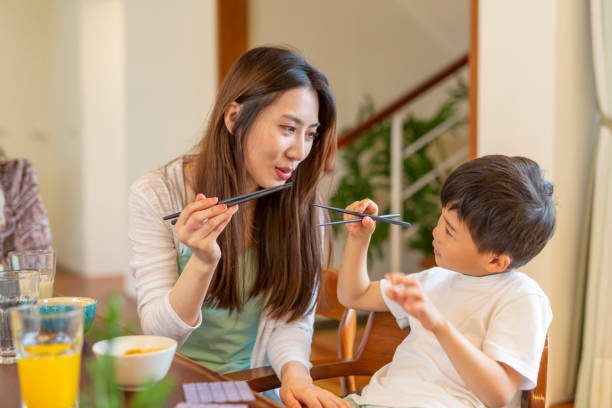 istock Mother Teaching Young Boy to Use Chopsticks 1162256929