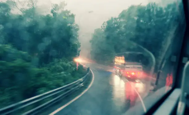 Blurred background with row of tree along highway motion blur at twilight in vintage color from window of car on rainy day