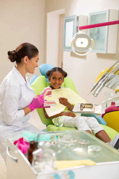 istock Smiling doctor using a dental model and toothbrush 1162266300