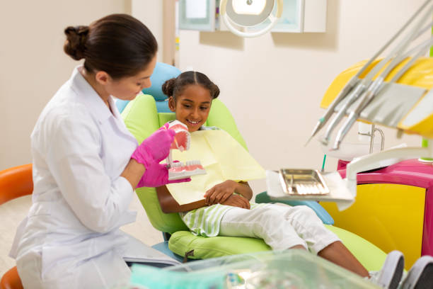 istock Dark-haired female doctor brushing an artificial teeth model 1162266305