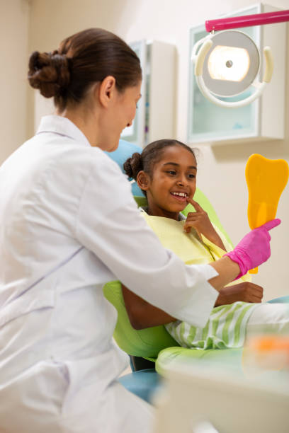 patient féminin assez jeune regardant dans le miroir - dentist teenager dental hygiene sitting photos et images de collection