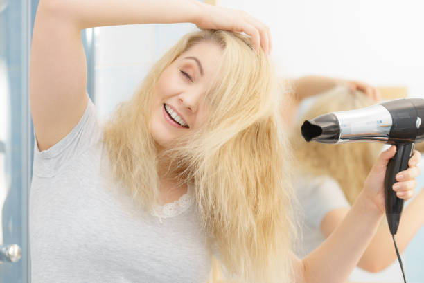 istock Blonde woman using hair dryer 1162269327