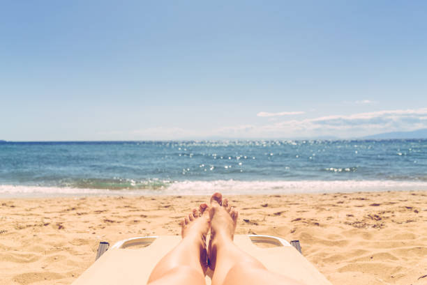 istock Female legs sunbathing on the beach 1162271406