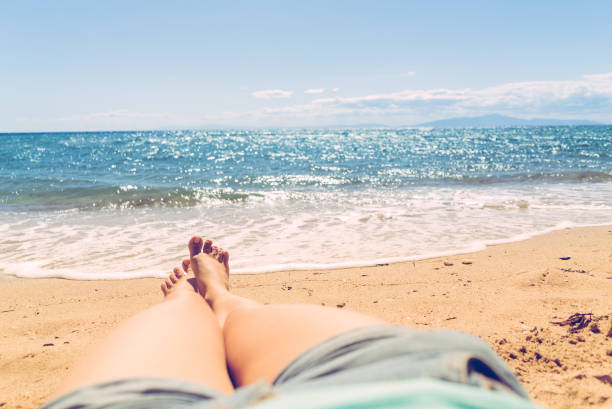 istock Female legs sunbathing on the beach 1162271418