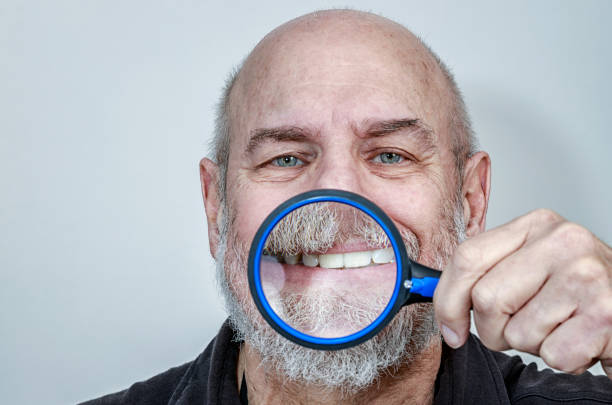 istock Senior Man Toothy Smile Exaggerated Through Magnifying Glass 1162271667