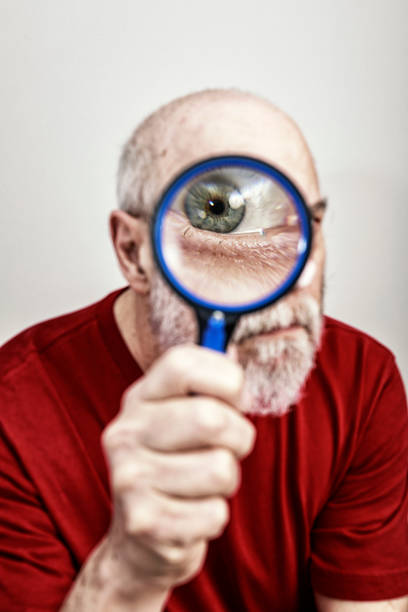 bizarre cyclops one-eyed senior man staring through magnifying glass - peeking analyzing staring watching imagens e fotografias de stock