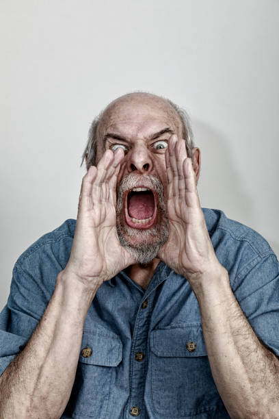 istock Furious Senior Man Hands Cupped Shrieking Threats at Camera 1162271744