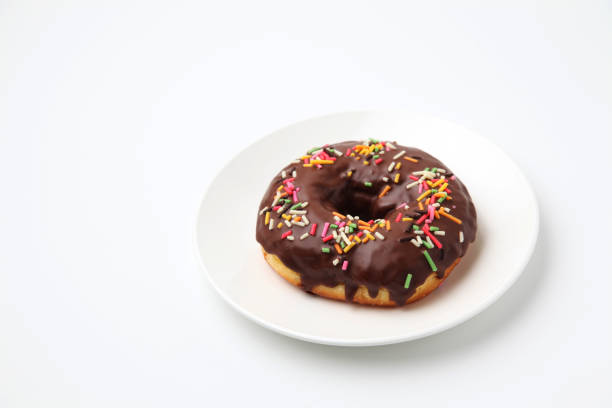 istock chocolate frosted doughnut on plate on white background 1162273611
