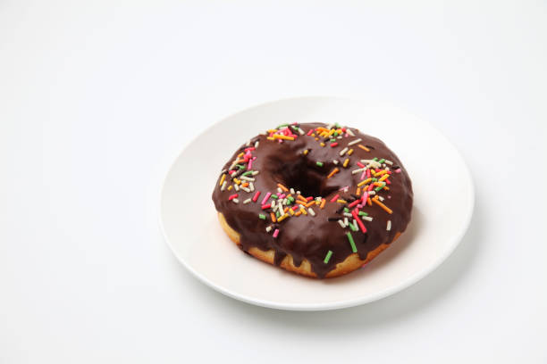 istock chocolate frosted doughnut on plate on white background 1162273724
