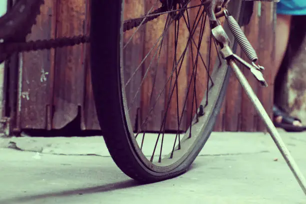 Amazing close up old bicycle front of antique house, wheel of bike rust, damaged with blurred background in vintage tone at China town, Vietnam