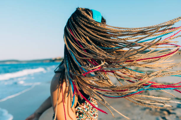 Woman with toulsed braided hair standing on beach.