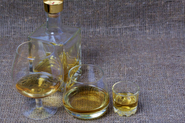 istock A bottle of strong alcohol. Glasses and a stack with a strong alcoholic beverage poured into them. Stand in a row. Against the backdrop of coarse linen fabric. 1162276784