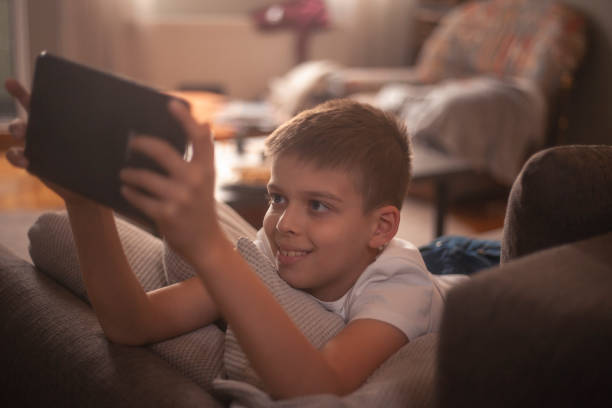 istock one happy and smiling boy using tablet, sitting in couch, relaxing in his home. 1162277517