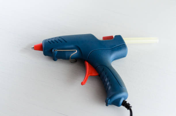 istock Blue glue gun and hot melt rods on white background 1162279738