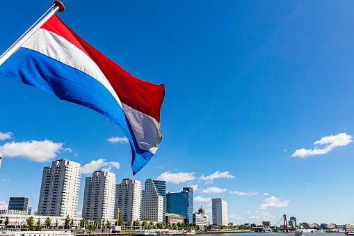 Netherlands flag waving, Highrise buildings background, sunny day in Rotterdam city center