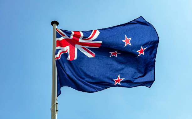 neuseeland-flagge winkt gegen klaren blauen himmel - zeeland stock-fotos und bilder